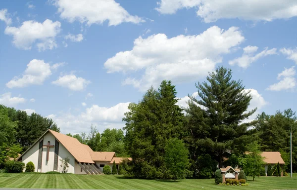 Modern kyrka ram tak, gräsmatta, träd, blå himmel — Stockfoto