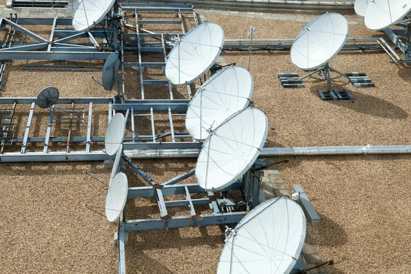 Verzameling van grote satellietschotels op vlakke grind dak — Stockfoto