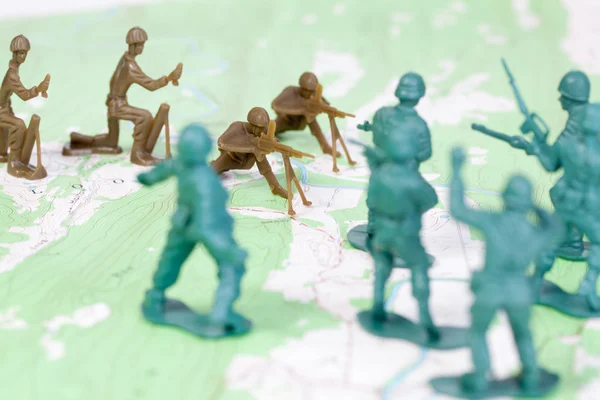 Hombres del ejército de plástico luchando en el mapa topográfico oponiéndose a la guerra de los lados —  Fotos de Stock