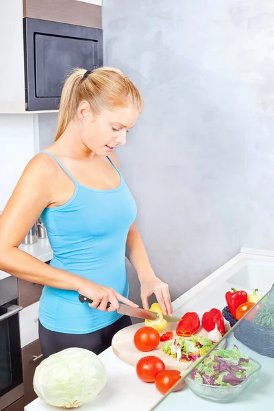 Mujer joven en cocina cortando verduras — Foto de Stock