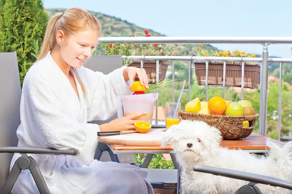 Woman making morning juice on terrace with her dog — Stock Photo, Image