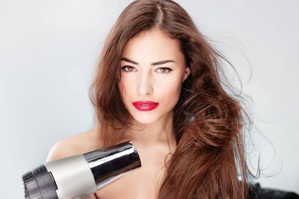Woman with long hair holding blow dryer — Stock Photo, Image
