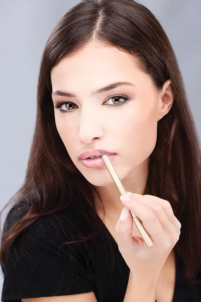 Mulher aplicando lápis cosmético em seus lábios — Fotografia de Stock