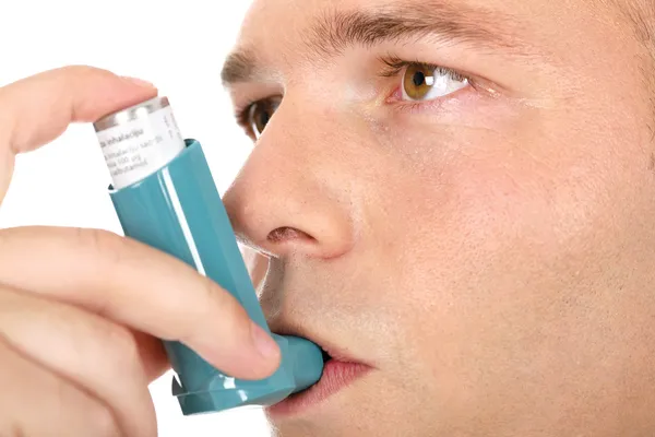 Крупный план человека с насосом во рту, против астмы — стоковое фото