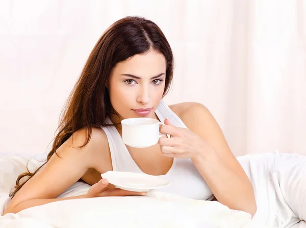 Mulher segurando xícara de café na cama — Fotografia de Stock