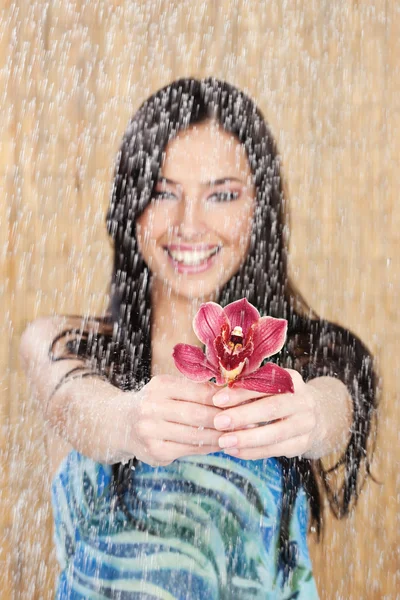 Menina feliz com orquídea vermelha sob gotas de água — Fotografia de Stock