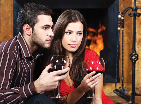Romantisch paar in de buurt van open haard drinken van rode wijn — Stockfoto
