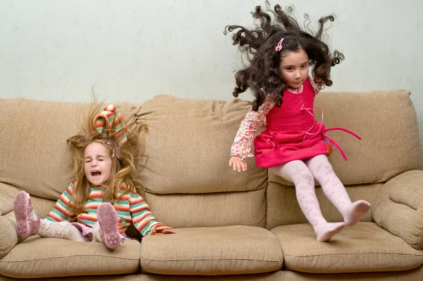 Two little girls jumping on sofa — Stock Photo, Image