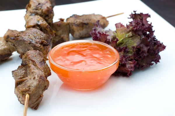 Kebabs on sticks with hot sauce — Stock Photo, Image