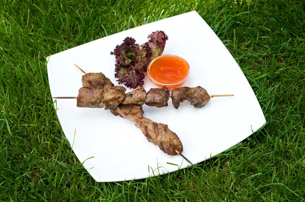 Kebabs on sticks with hot sauce — Stock Photo, Image