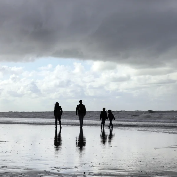 Glückliche Familie spaziert am Strand entlang — Stockfoto