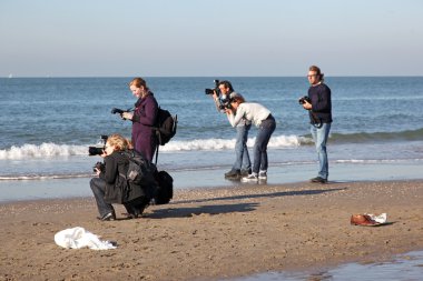 Five photographers on a beach clipart