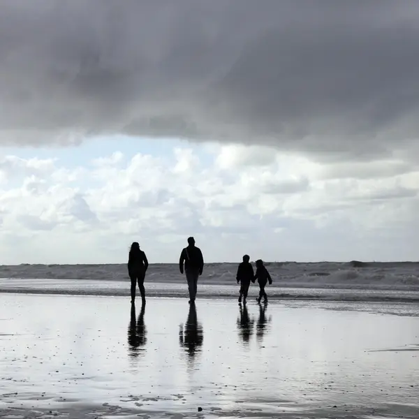 Felice famiglia passeggiando lungo la spiaggia — Foto Stock