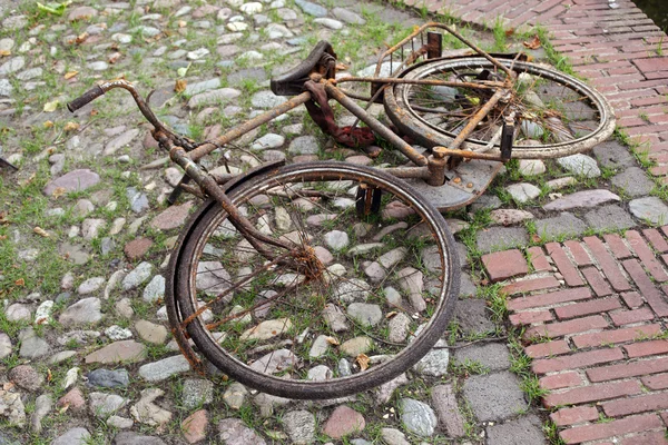 Very rusty bicycle lying on cobble-stones
