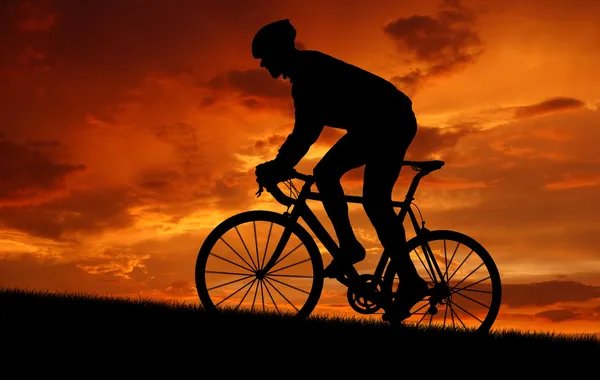 日没時の道の自転車に乗ってのサイクリスト — ストック写真