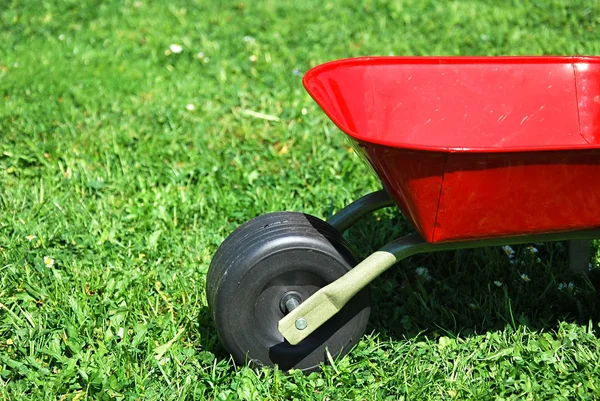 O carrinho de mão vermelho no jardim . — Fotografia de Stock