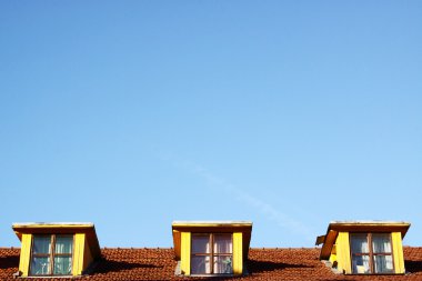 mavi gökyüzünün altında çatıda üç pencere