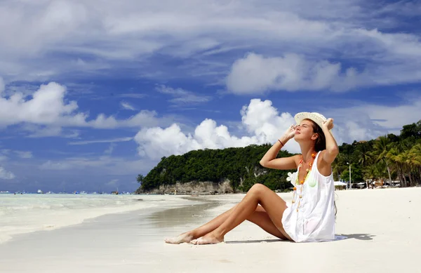 Tropikal plaj kum üzerine oturan şapkalı kız attracrive — Stok fotoğraf