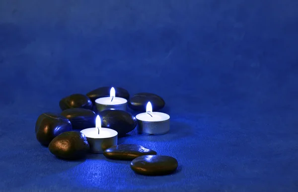 点燃的蜡烛放在一个蓝色的背景上 — 图库照片