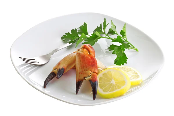 Krabbenkrallen, Zitronenkeile und ein Zweig Petersilie auf einem Teller. — Stockfoto