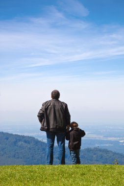 Father and son looked into the distance from the cliff. clipart