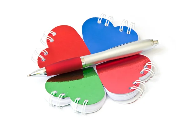 Four heart-shaped notepad and pen. — Stock Photo, Image
