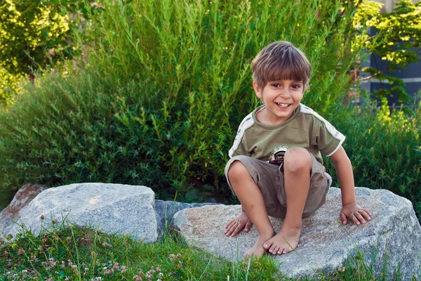 Portrait of a young boy, sitting on a rock. — Stock Photo, Image