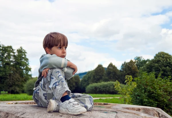 Маленький мальчик, сидящий на упавшем дереве — стоковое фото