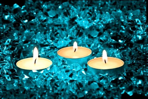 点燃的蜡烛放在一个蓝色的背景上 — 图库照片