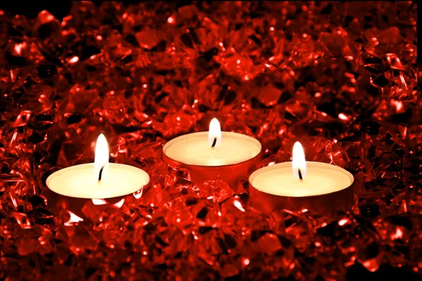 点燃的蜡烛放在红色的背景上 — 图库照片