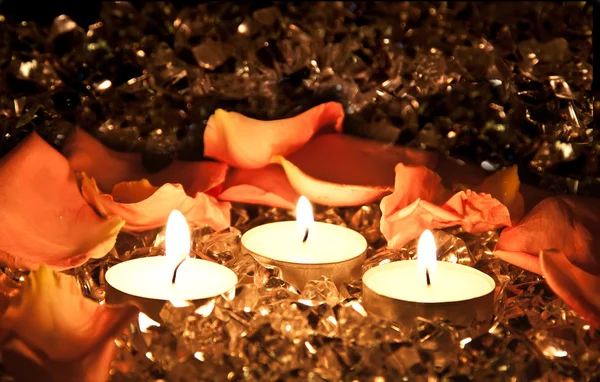 Brennende Kerzen auf goldenem Hintergrund mit Rosenblättern. — Stockfoto