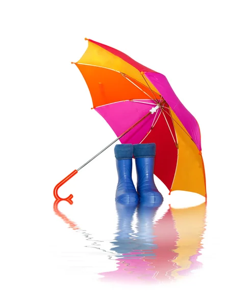 Rubber boots and a colorful umbrella with reflection in water — Stock Photo, Image