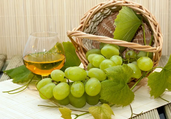 Grappolo d'uva bianca in un cesto e un bicchiere di vino — Foto Stock