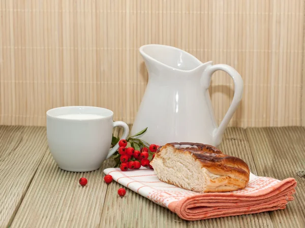 Pitcher of milk and a piece of cake on a wooden table — Stock Photo, Image