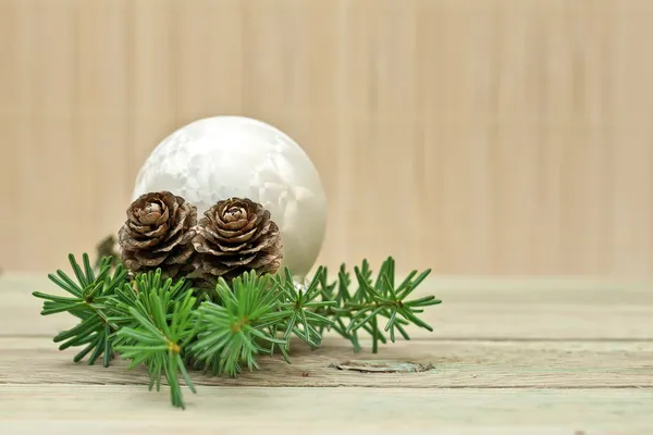 Ramo di pino con pigne e decorazioni natalizie su fondo tavola — Foto Stock