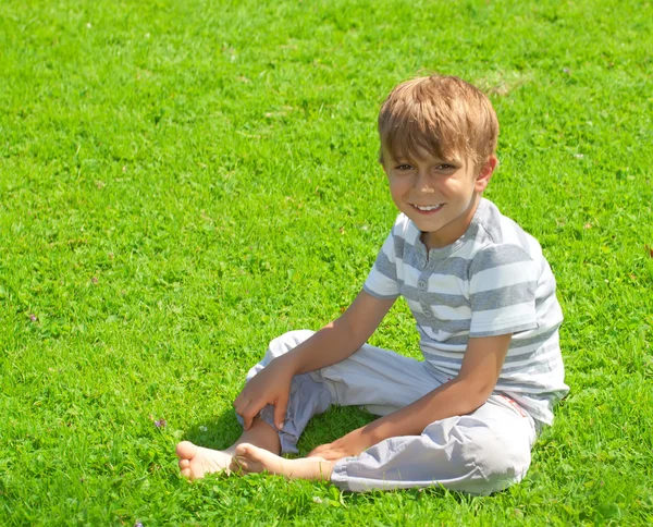 Portrait of a young boy sitting in the grass — Stock Photo, Image