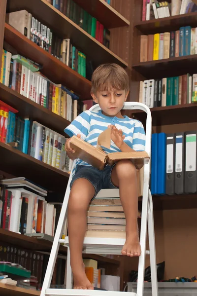 Junge in Bibliothek liest Buch — Stockfoto