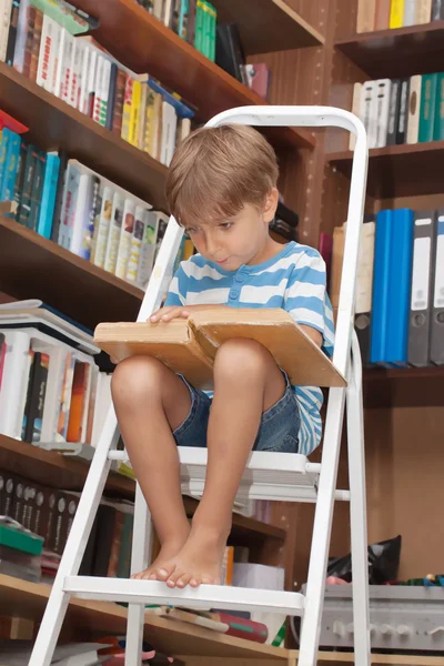 Jongen in bibliotheek lezen van boek — Stockfoto