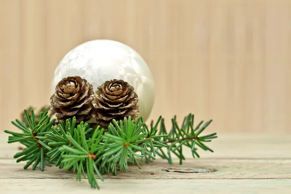 Kiefernzweig mit Tannenzapfen und Weihnachtsdekoration auf Bretthintergrund Stockfoto