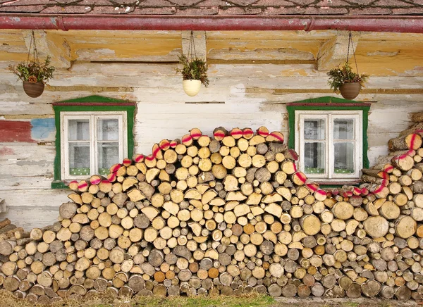 Stack of wood near old cottage windows — Stock Photo, Image