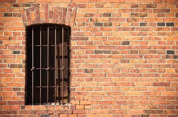 Old brick wall with window and iron bars