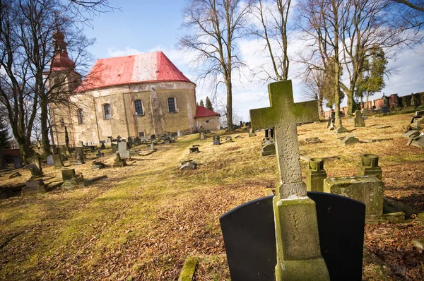 Кладбищная сцена с крестом и красивой церковью — стоковое фото