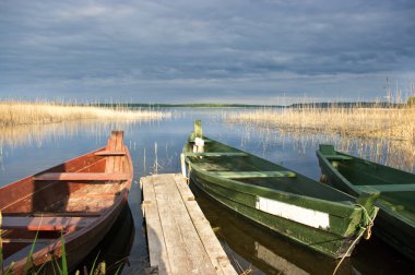 Scene with two boats, lake and pier clipart