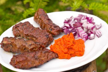 Traditional cevapcici with ajvar paste and red onion clipart