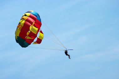 Silhouette of man with parachute on the sky clipart