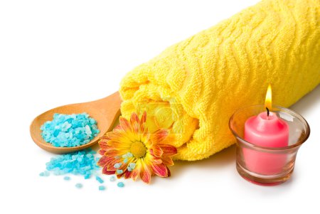 Serviette, sel de bain bleu, bougie et fleur 