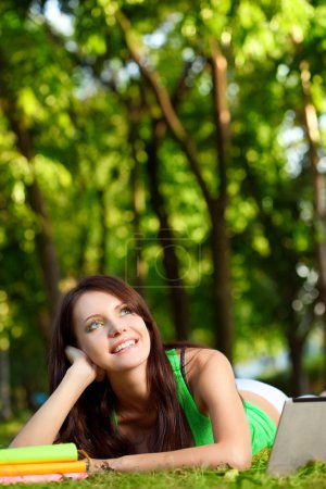 Femme rêveuse allongée sur l'herbe 