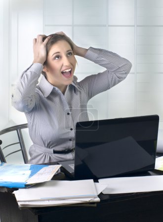 Femme d'affaires excitée au bureau avec ordinateur portable 
