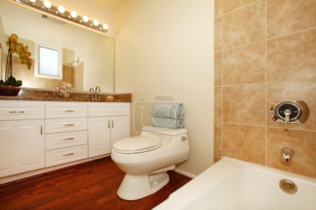 Salle de bain avec carreaux de céramique beige et plancher de bois .