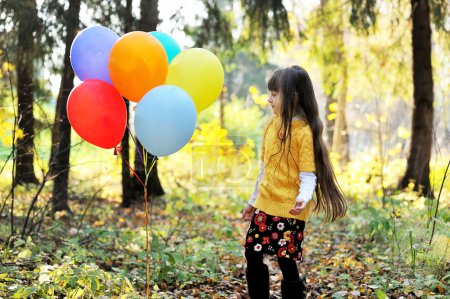 Enfant fille avec des ballons dans la forêt d'automne 